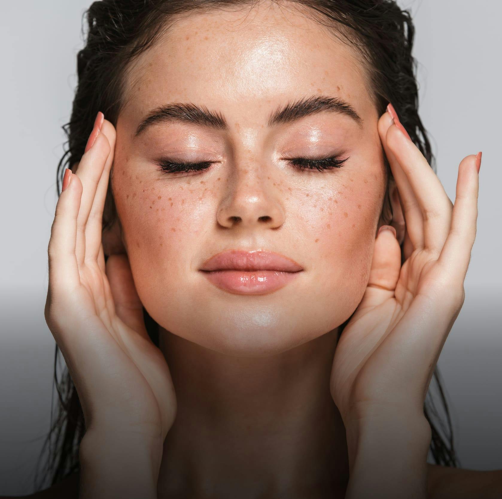 woman touching the sides of her face with her eyes closed