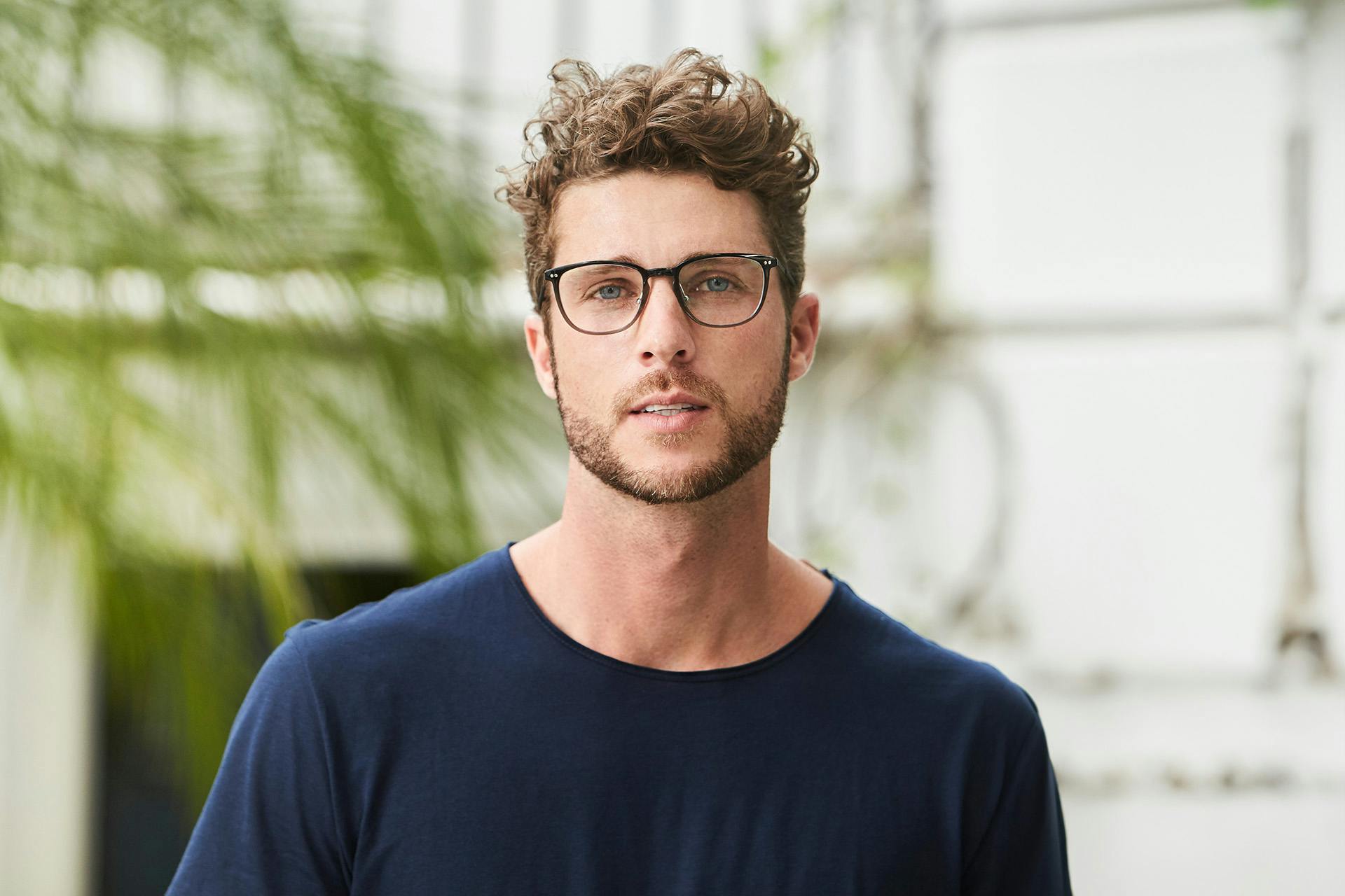 man with curly hair wearing glasses