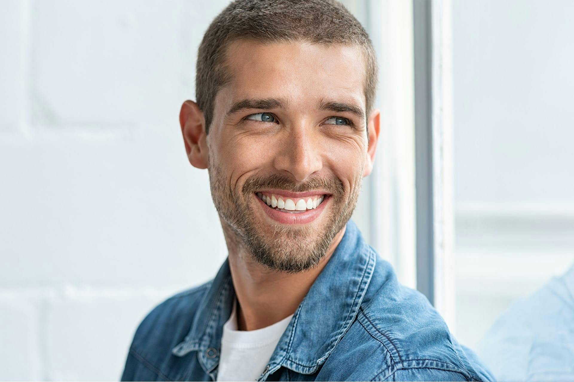 handsome man smiling wearing a blue denim shirt