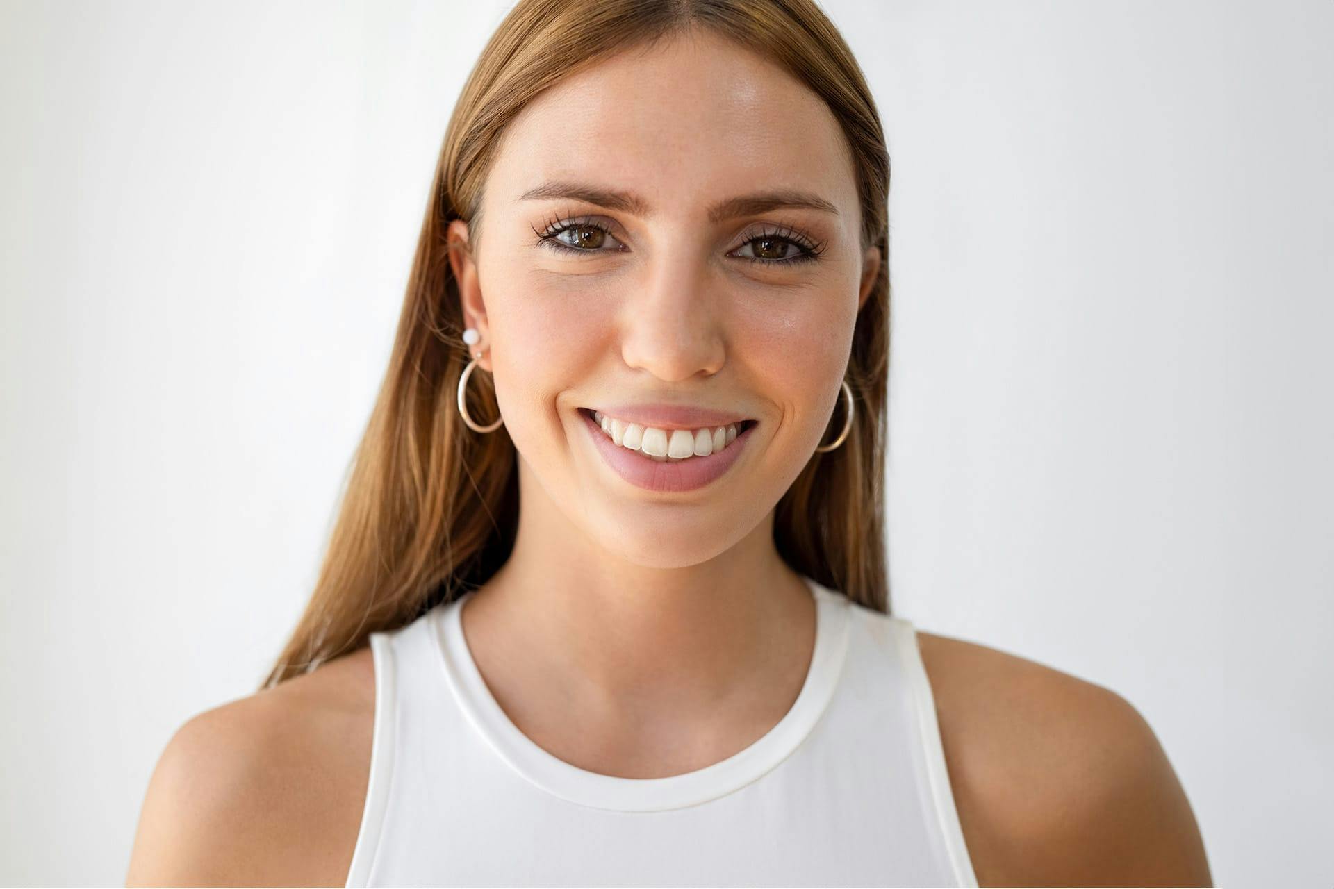 woman wearing gold hoop earrings and a white tank top