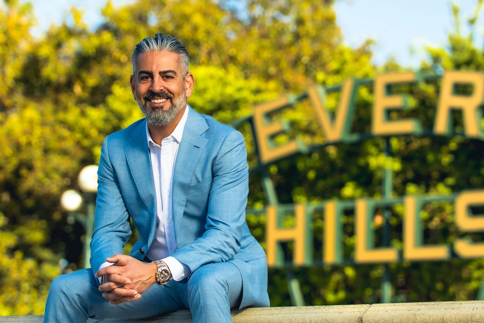 Dr. Firouz sitting in front of the Beverly Hills city sign