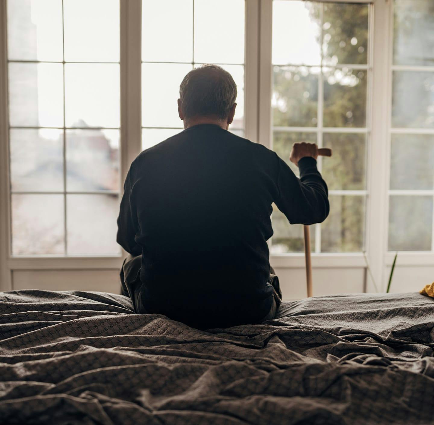 Man holding cane and looking out window