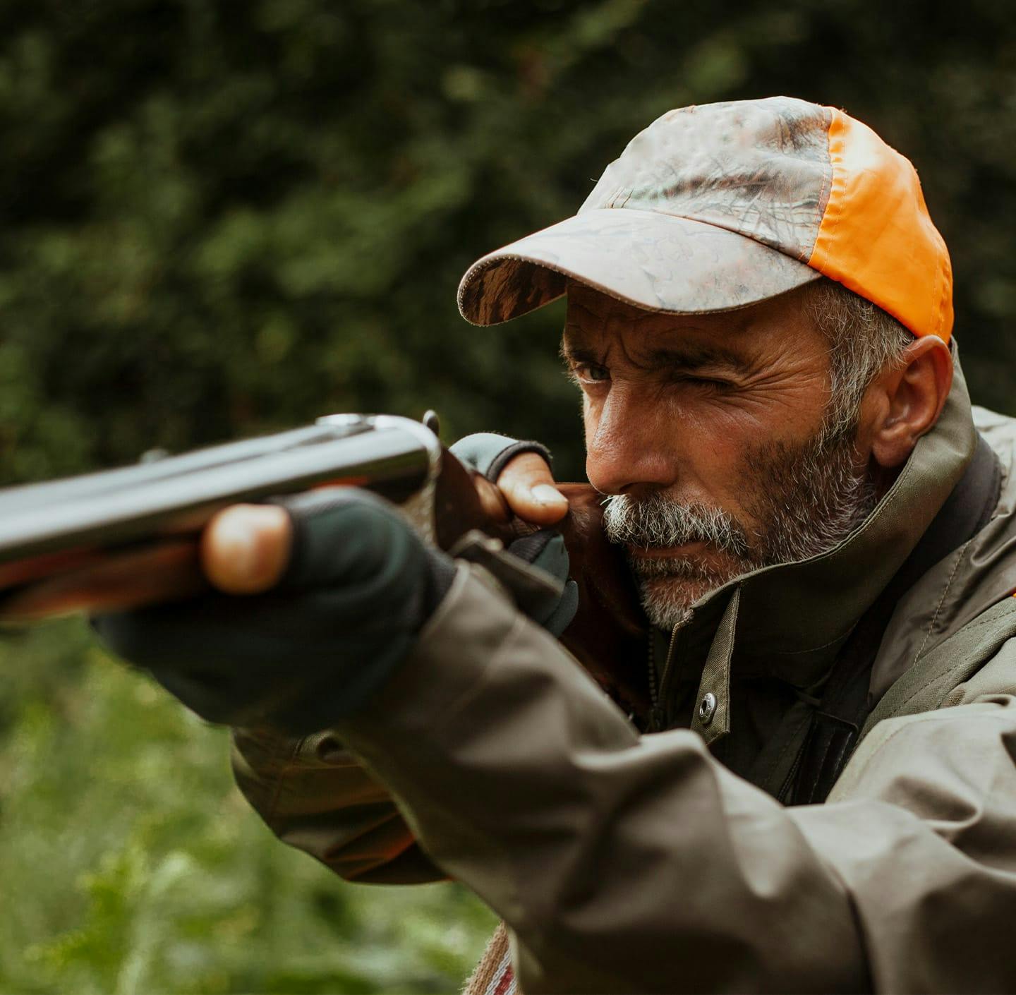 Man in cap pointing rifle