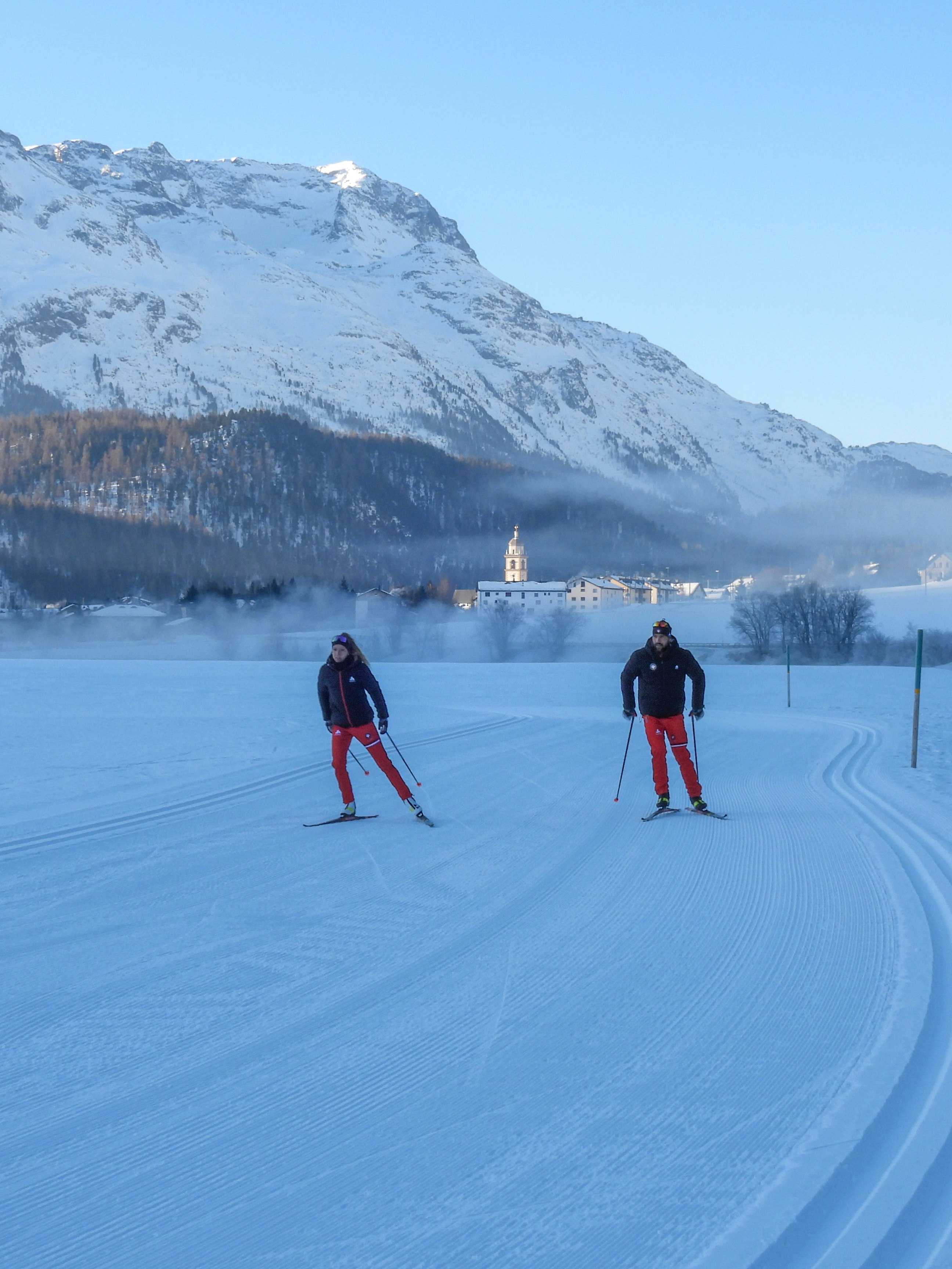 Cross-country skiers skating in front of snowy mountains