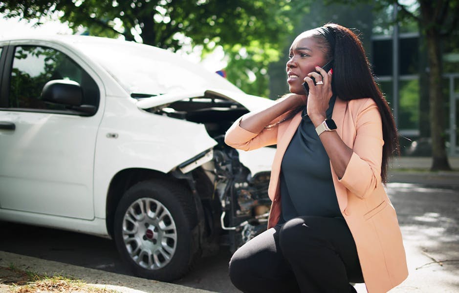 woman on phone near wrecked car