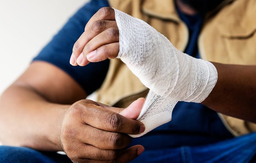 man wrapping his hand and wrist in guaze