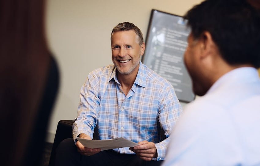 client smiling at attorneys while holding paperwork
