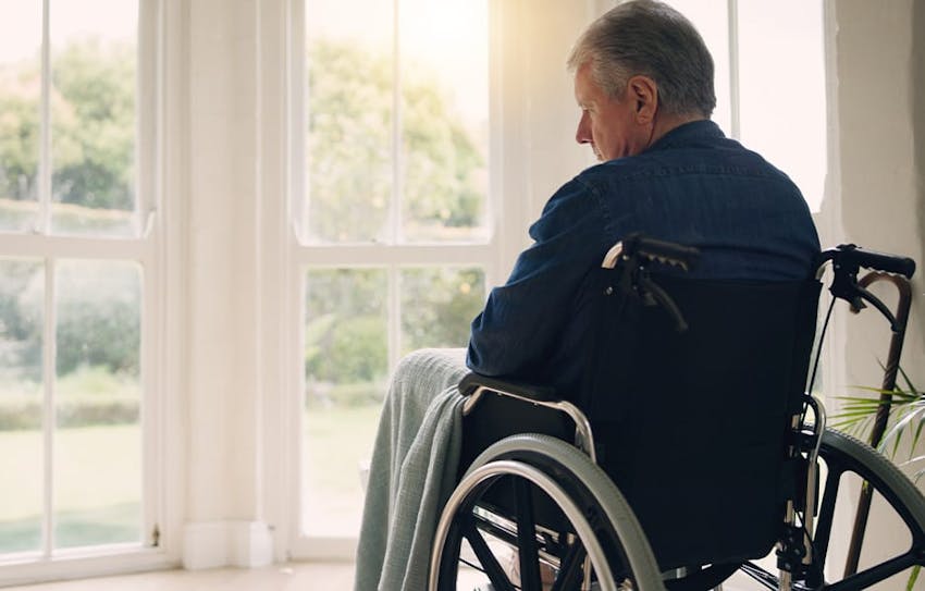 man in wheelchair looking out window