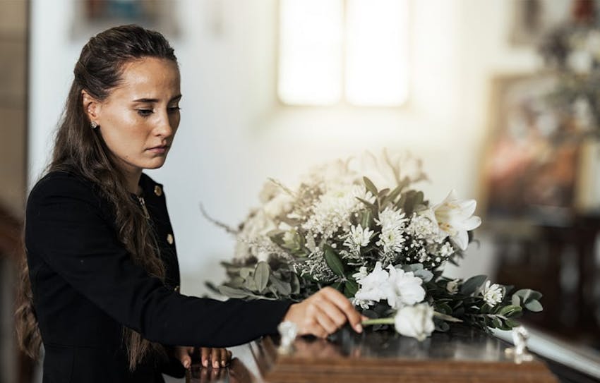 woman placing flower on casket