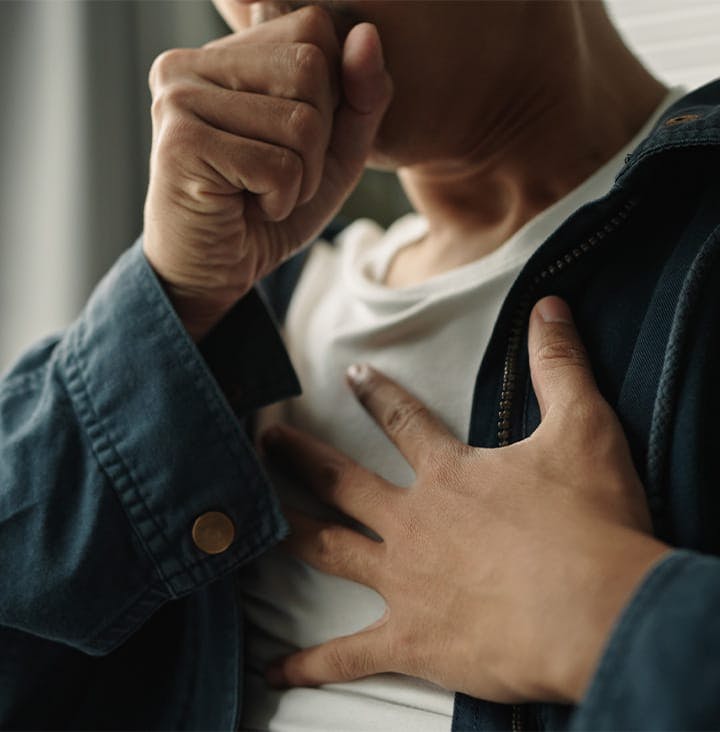 person with hand on their chest as they cough