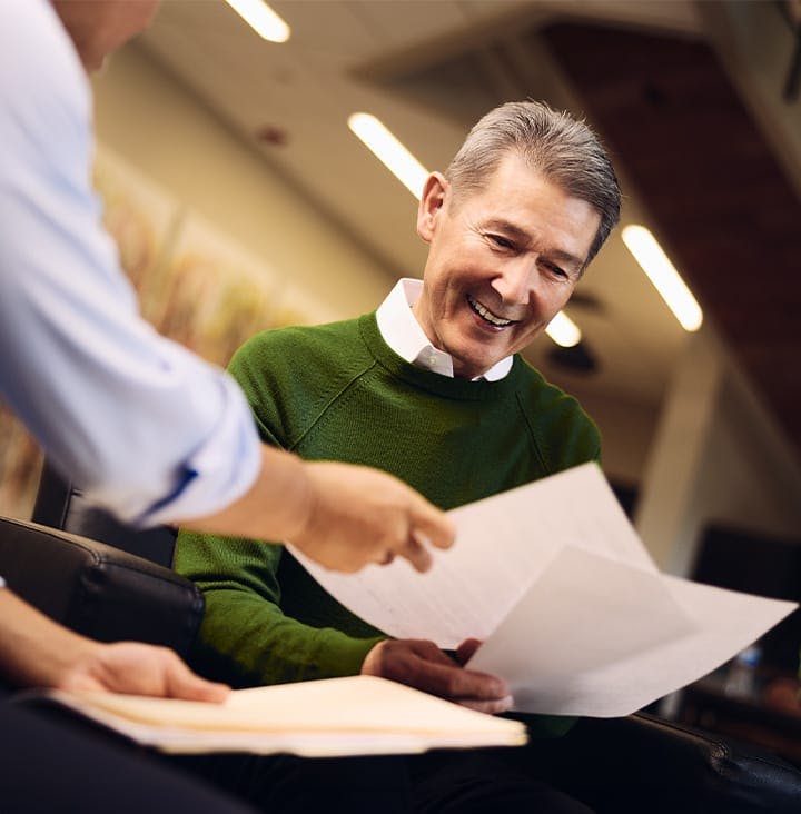 client smiling at papers that are being handed to him