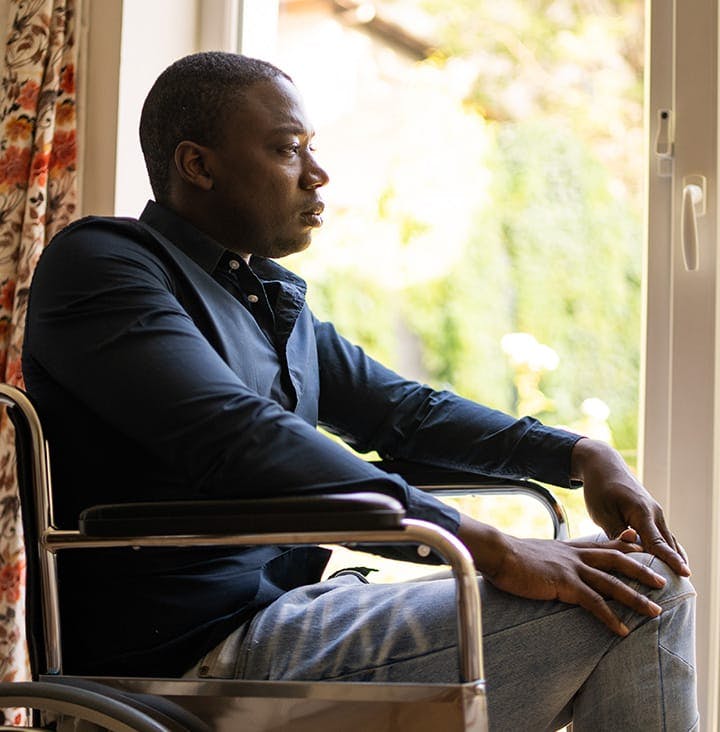 man in wheelchair looking out glass slide door