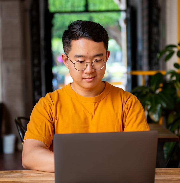 man in yellow shirt on laptop