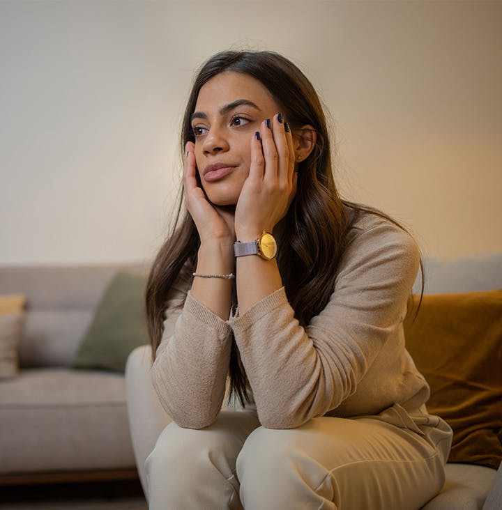 woman with hands on her face as shes sitting down