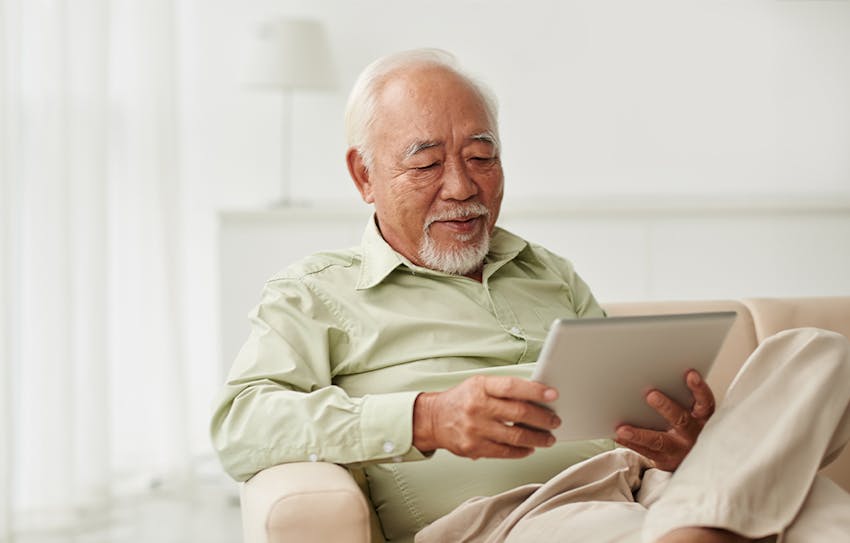 older man on couch looking at ipad