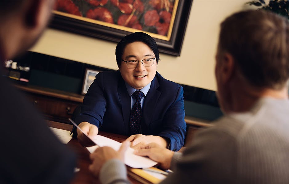 Andrew Kim handing paperwork to client