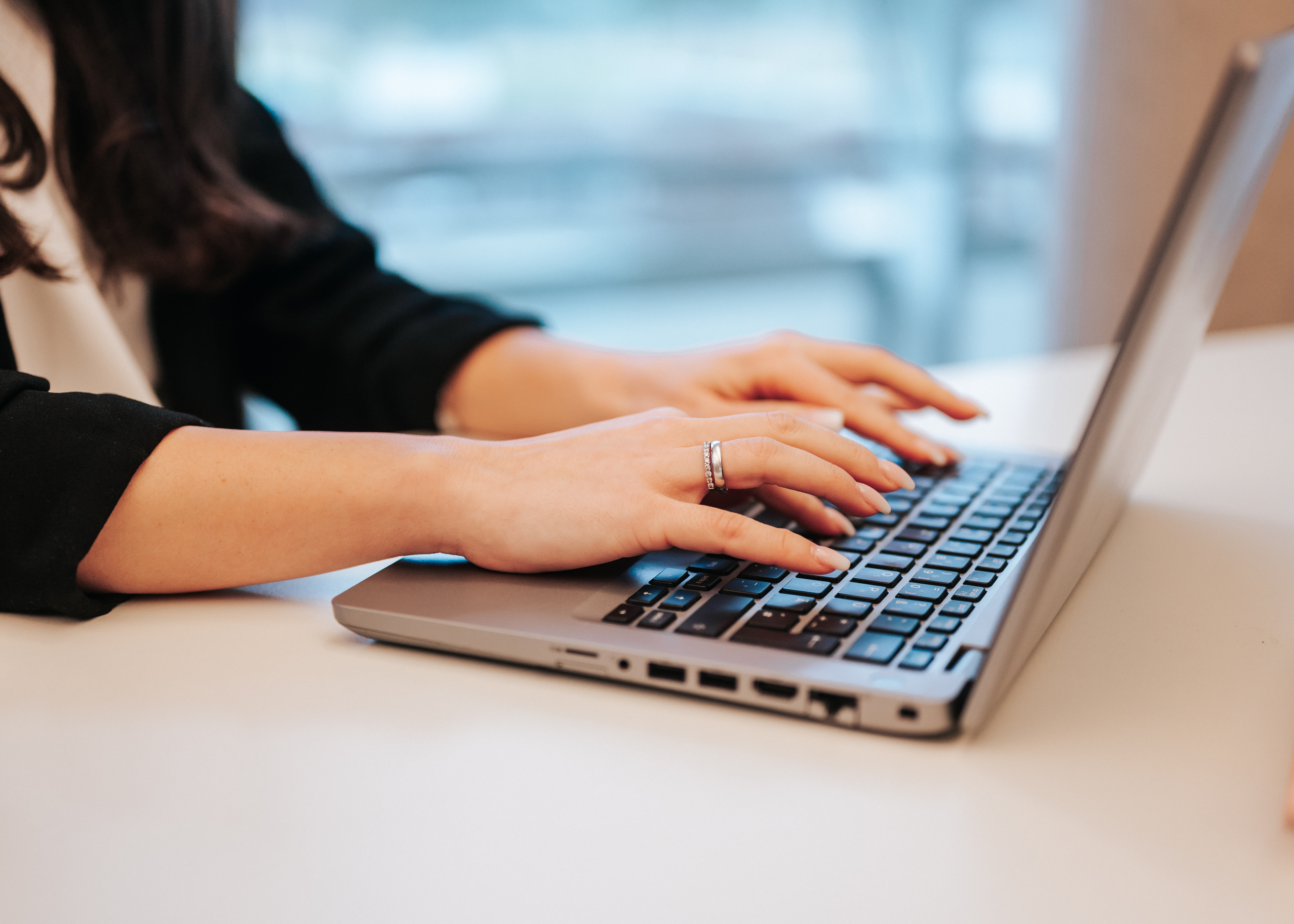 Mitarbeiterin der Baaderbank tippt auf Laptop-Tastatur im modernen Büro.