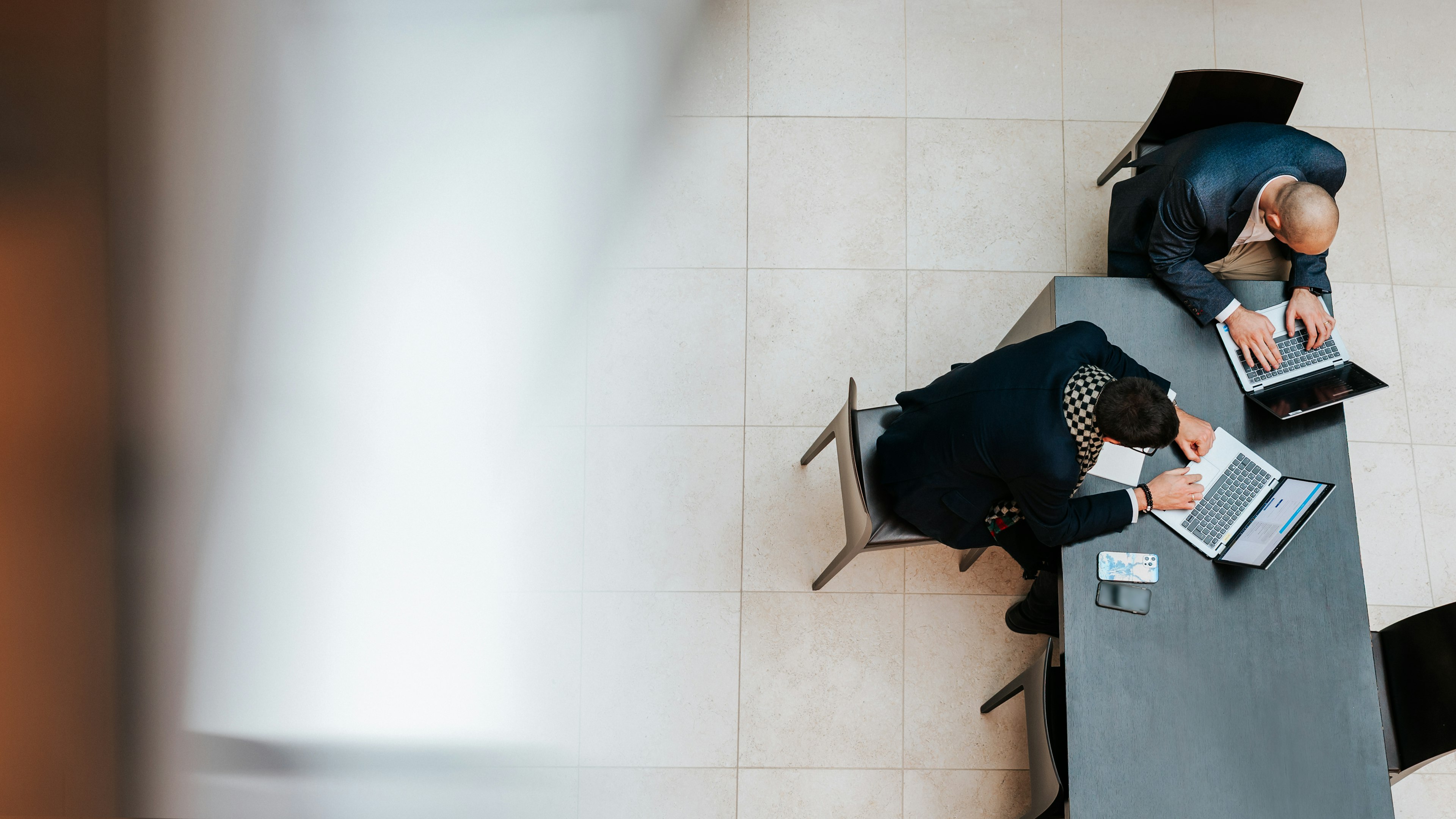 Zwei Baaderbank Mitarbeiter arbeiten im Banking Bereich an Laptops in moderner Büroumgebung.