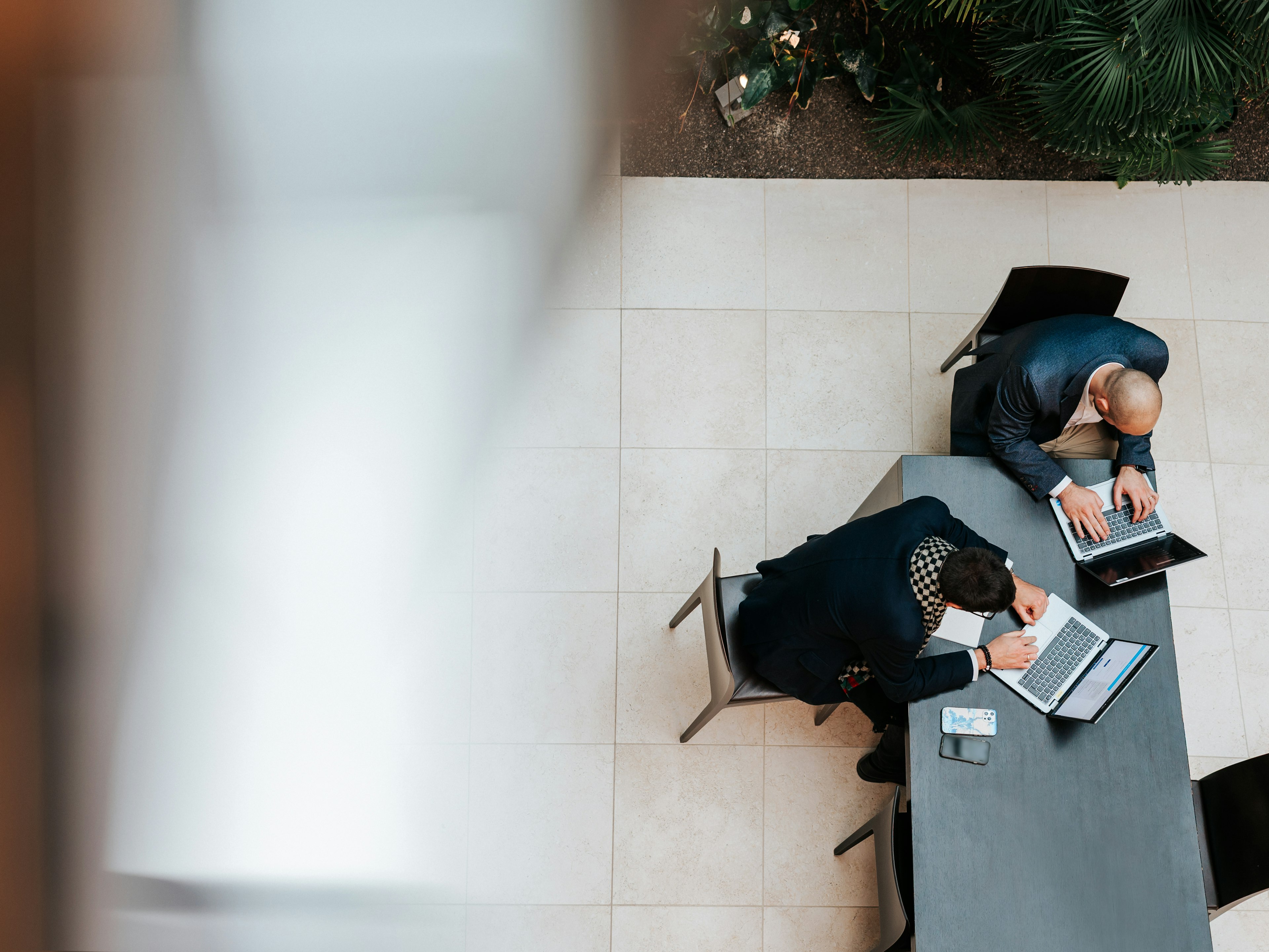 Zwei Baaderbank Mitarbeiter arbeiten im Banking Bereich an Laptops in moderner Büroumgebung.