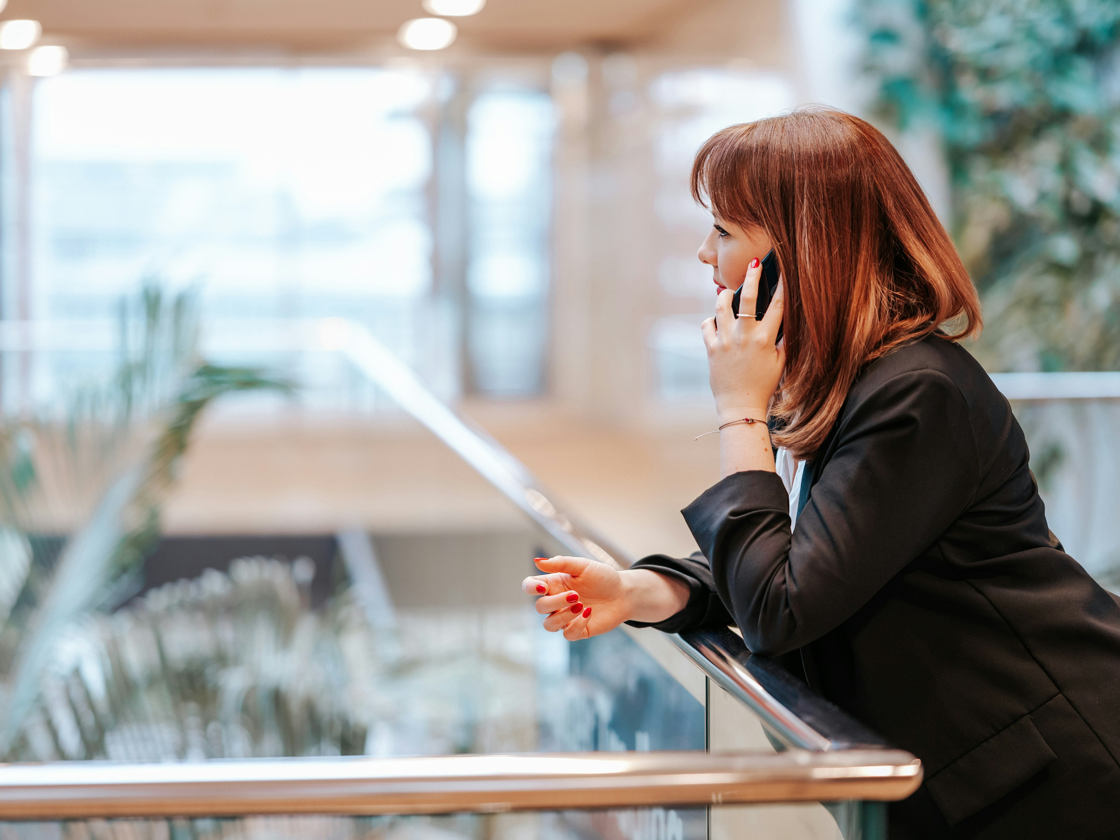 Mitarbeiterin der Baaderbank im schwarzen Blazer telefoniert mit dem Smartphone im modernen Bürogebäude.
