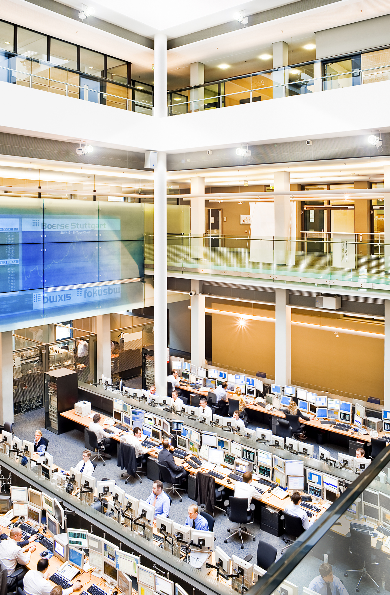Börsensaal mit vielen Monitoren und Händlern, große digitale Anzeigetafel mit Schrift „Boerse Stuttgart“.