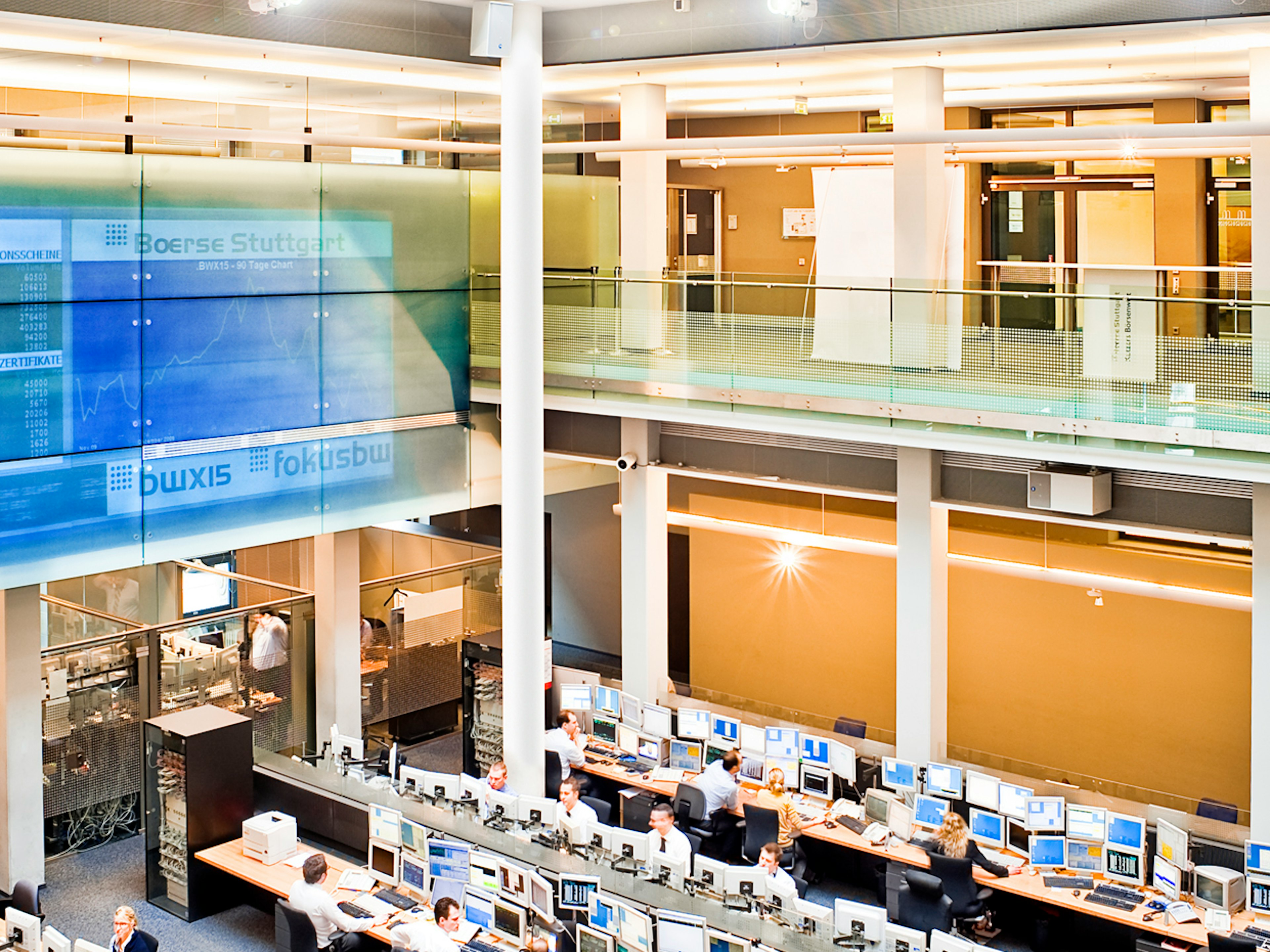 Börsensaal mit vielen Monitoren und Händlern, große digitale Anzeigetafel mit Schrift „Boerse Stuttgart“.
