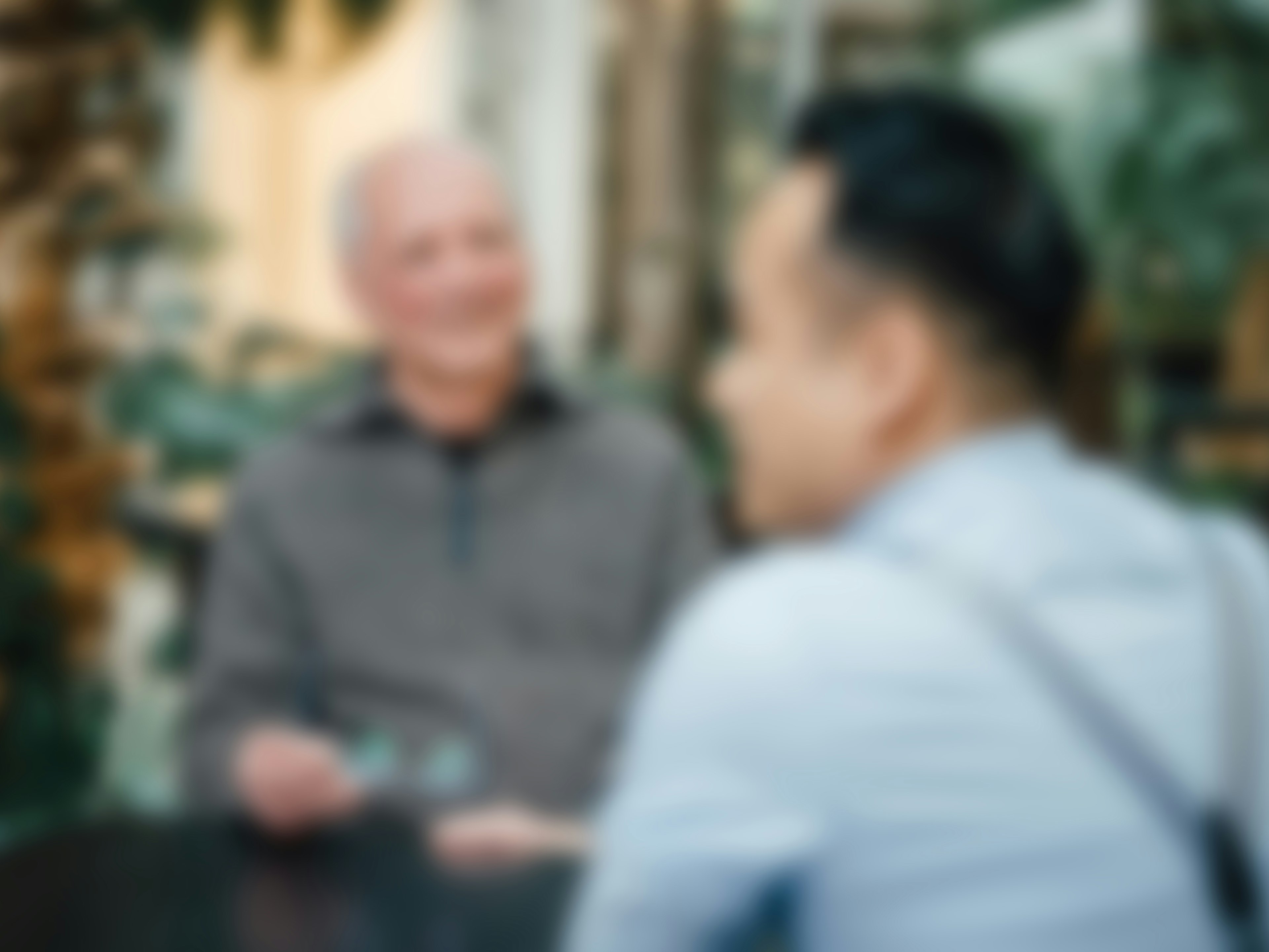 Verschwommene Aufnahme von zwei Personen im Gespräch in einer modernen Umgebung.