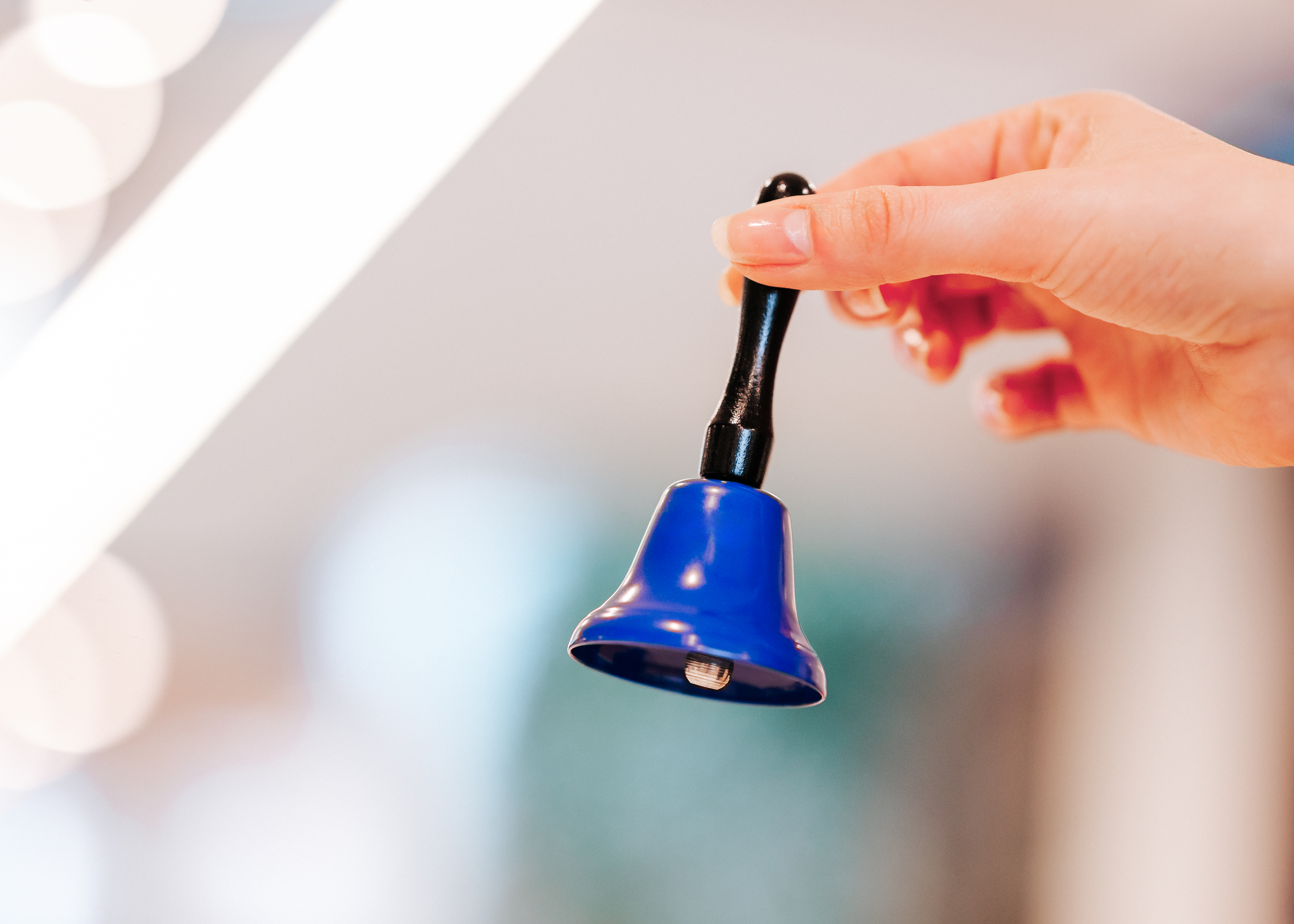 Detailaufnahme einer Hand mit blauer Glocke, der Hintergrund ist verschwommen.