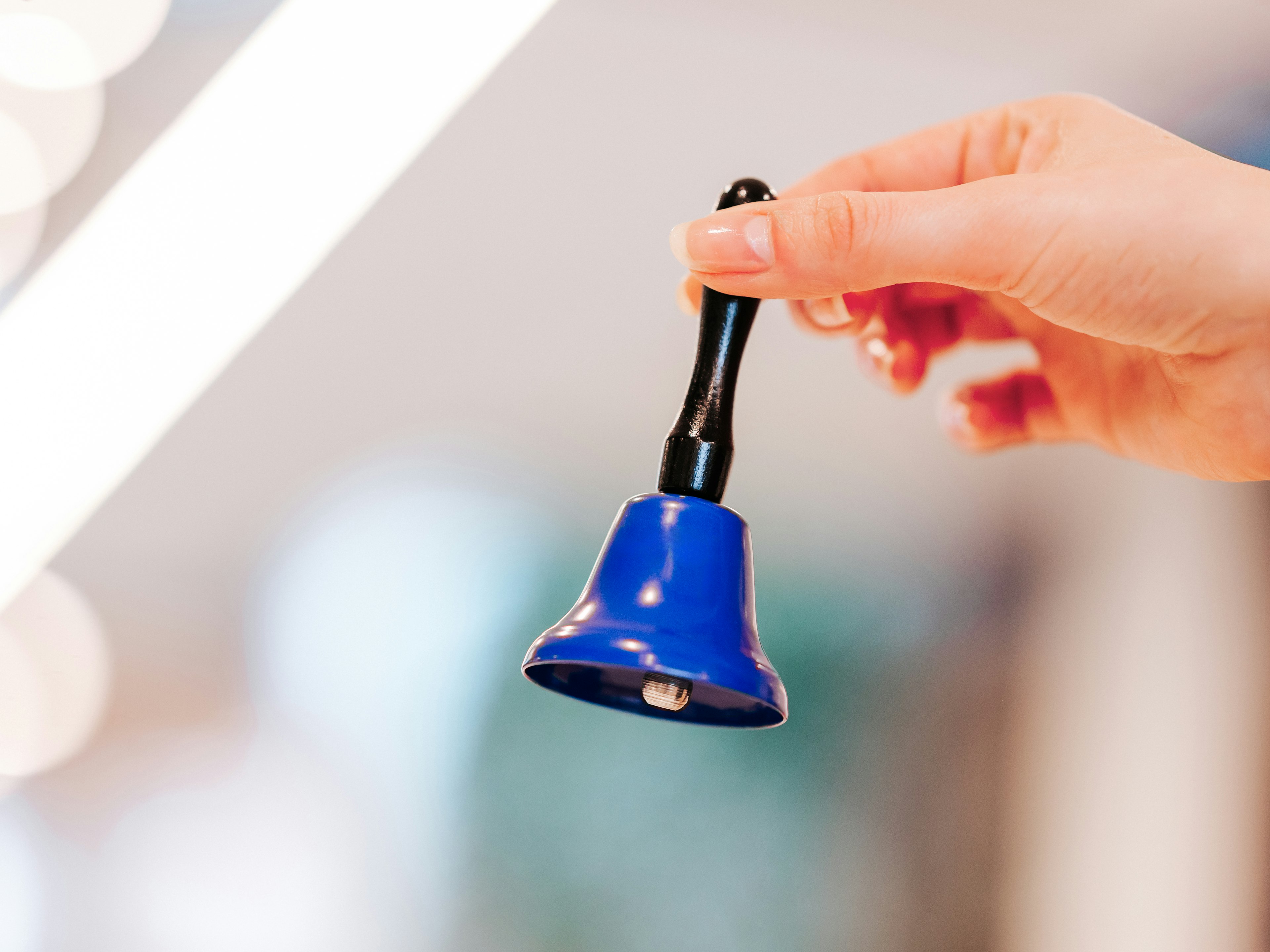 Detailaufnahme einer Hand mit blauer Glocke, der Hintergrund ist verschwommen.