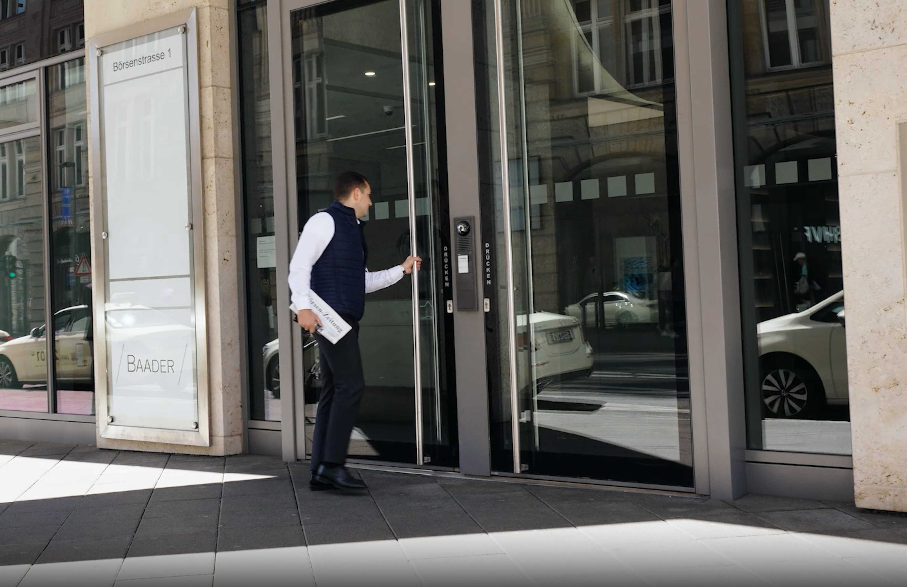 Ein Mann in Businesskleidung betritt durch eine Glastür ein Gebäude an der Börsenstraße 1.