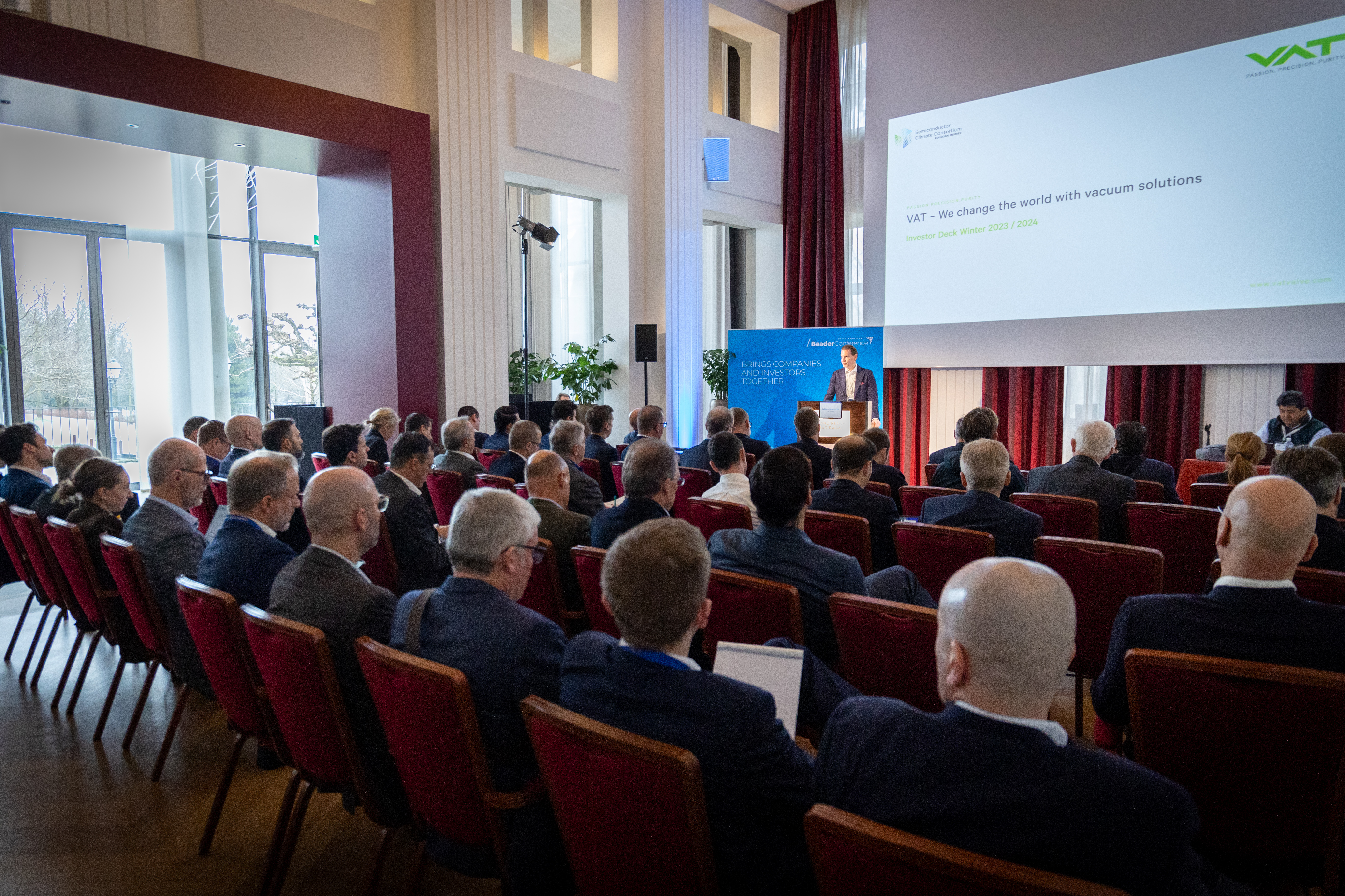 Konferenzsaal mit Vortragendem und Publikum, Teil einer Banking-Veranstaltung der Baaderbank.