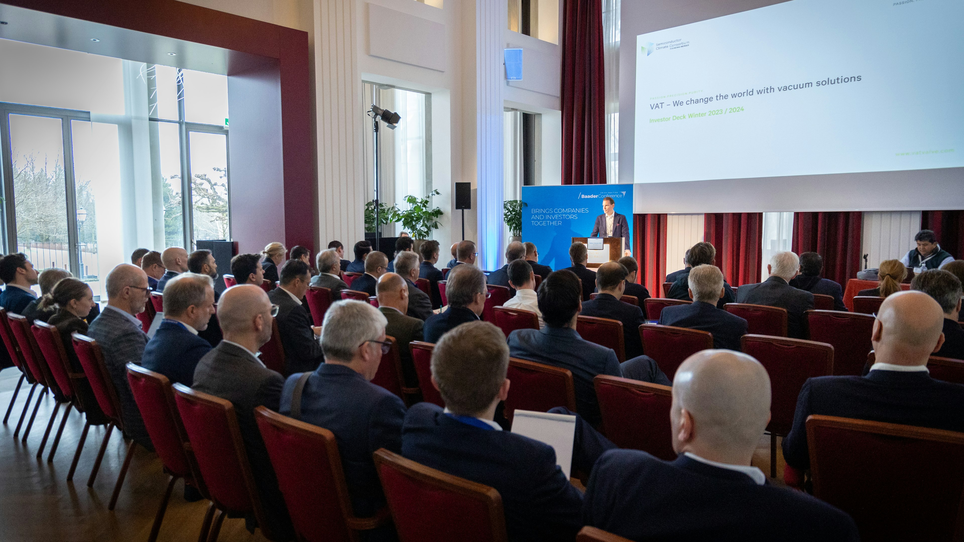 Konferenzsaal mit Vortragendem und Publikum, Teil einer Banking-Veranstaltung der Baaderbank.