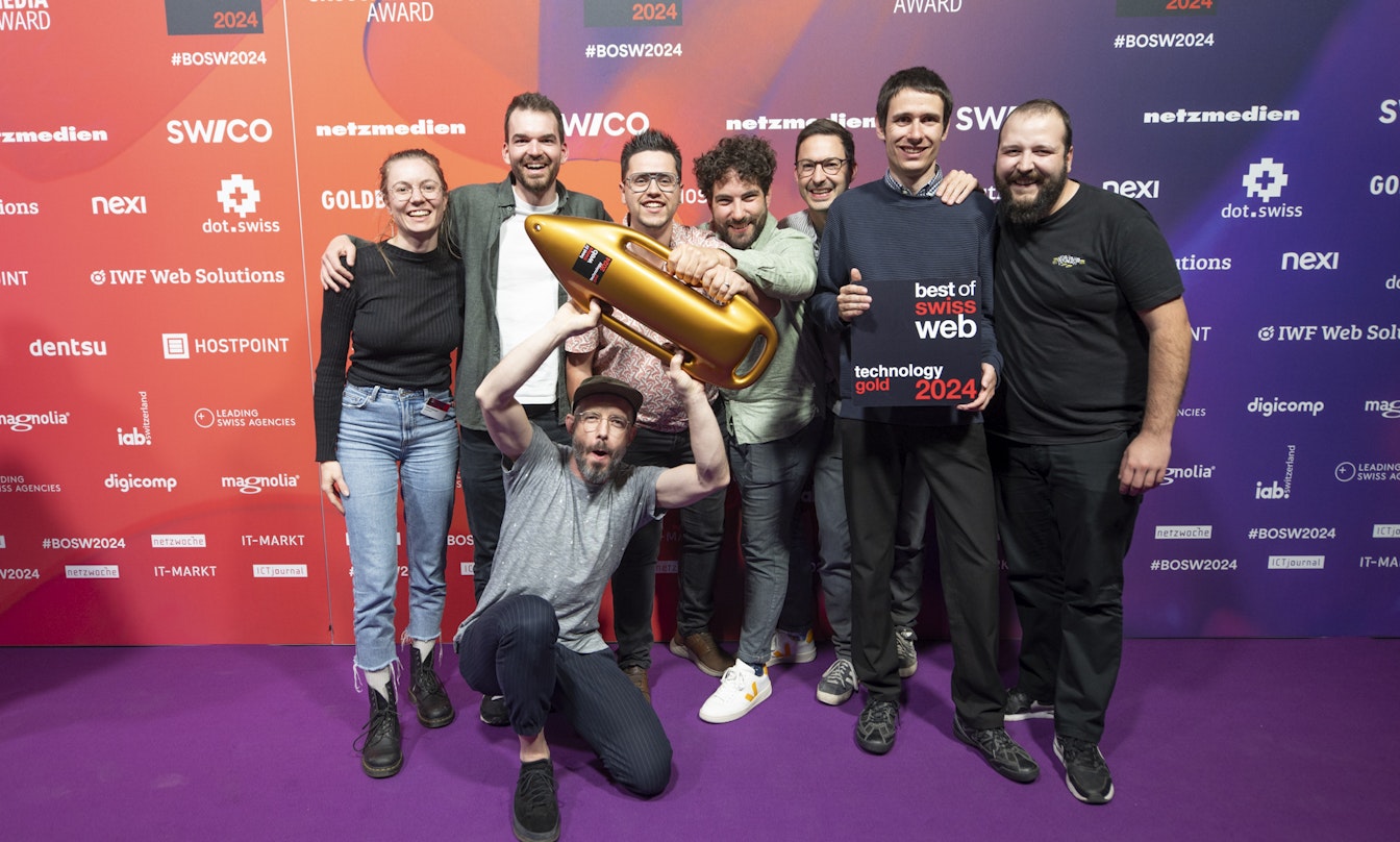 Gold bei Best of Swiss Web für smartive und Frontify Eine Gruppe von acht Personen posiert gemeinsam auf einem violetten Teppich und hält eine goldene Trophäe in Raketenform und eine Plakette mit der Aufschrift „Best of Web Technology Gold 2024“.