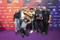 Eine Gruppe von acht Personen posiert gemeinsam auf einem violetten Teppich und hält eine goldene Trophäe in Raketenform und eine Plakette mit der Aufschrift „Best of Web Technology Gold 2024“.