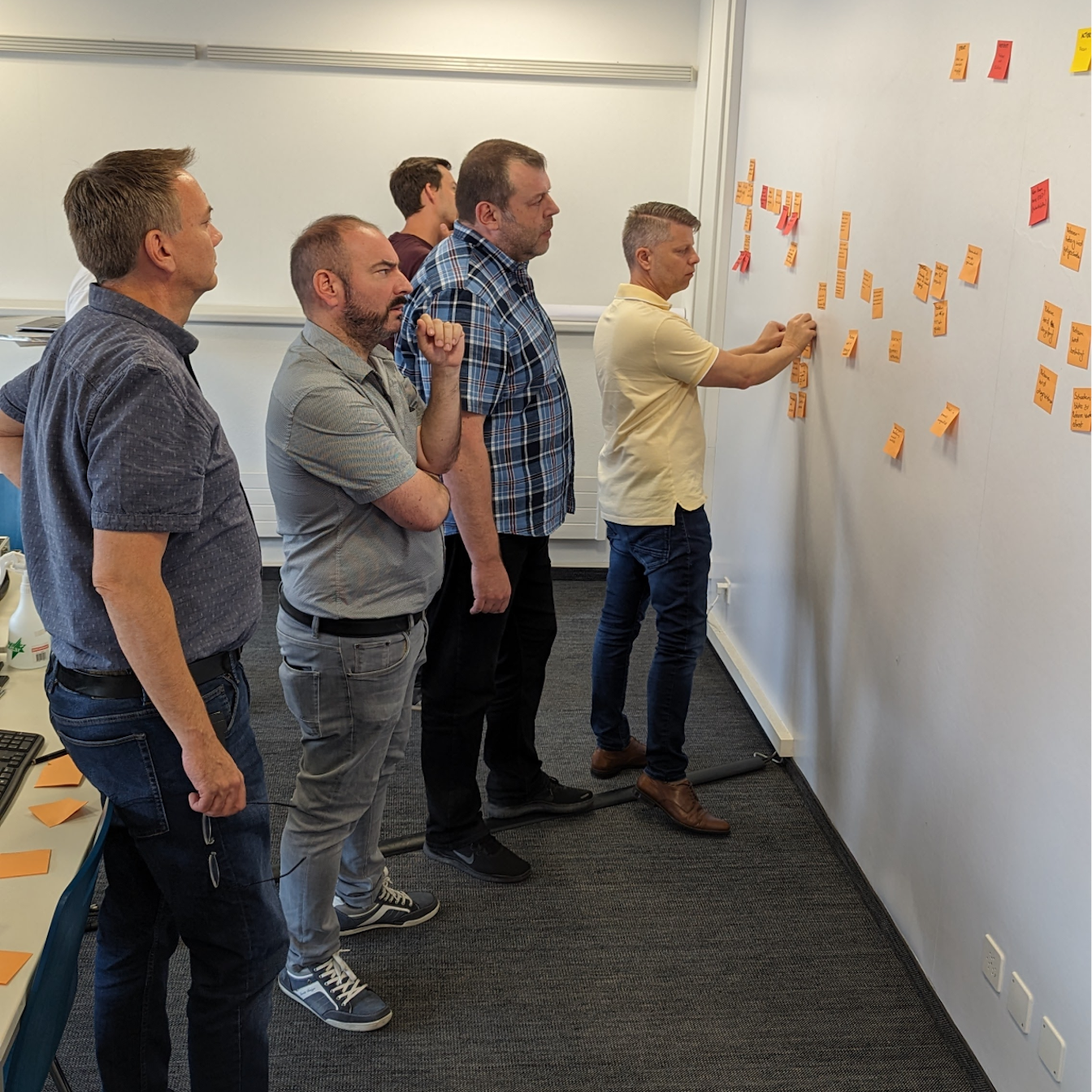 Fünf Personen vor einer Wand mit Post-Its.