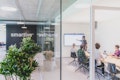 Ein Mann steht und präsentiert drei sitzenden Kollegen in einem modernen Büro mit Glaswänden und Grünpflanzen Informationen auf einem Bildschirm. An der Wand hinter ihnen ist das Wort „smartive“ zu sehen.