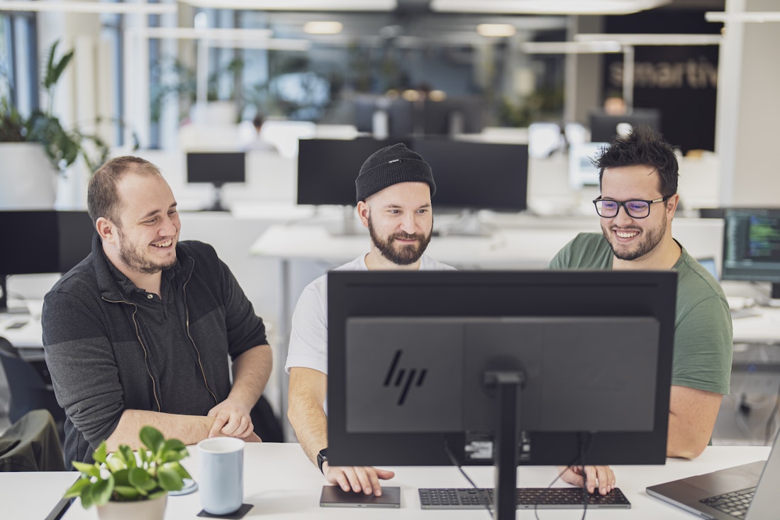 Drei smartive-Mitarbeitende besprechen etwas am Computer.