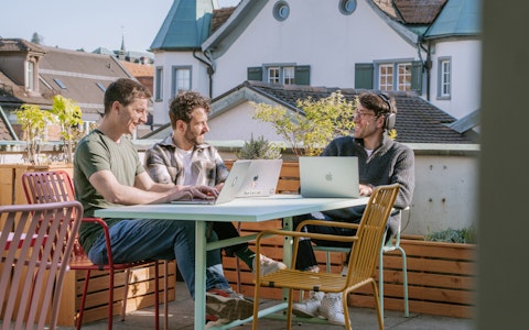 Auf unserer Dachterasse am Standort in St.Gallen Drei Mitarbeiter von smartive sitzen mit ihren Laptops auf der sonnigen Dachterrasse von smartive in St. Gallen