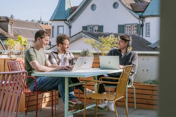 Drei Mitarbeiter von smartive sitzen mit ihren Laptops auf der sonnigen Dachterrasse von smartive in St. Gallen