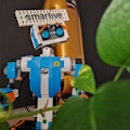 Lego-Roboter mit 'smartive'-Schild im Hintergrund, umgeben von grünen Pflanzen.