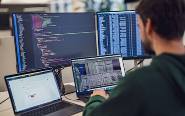 Eine Person arbeitet an einem Schreibtisch mit mehreren Bildschirmen, auf denen Code und Daten angezeigt werden.
(Hinweis: Der von Ihnen bereitgestellte Text enthält keine „ß“-Zeichen, der Inhalt bleibt also unverändert.).