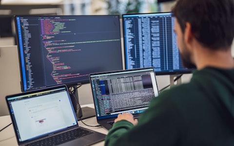 Eine Person arbeitet an einem Schreibtisch mit mehreren Bildschirmen, auf denen Code und Daten angezeigt werden.
(Hinweis: Der von Ihnen bereitgestellte Text enthält keine „ß“-Zeichen, der Inhalt bleibt also unverändert.).