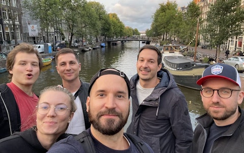 Smarties an der Awwwards Konferenz 2022 Eine Gruppe von sechs Personen macht ein Selfie auf einer Brücke mit einem Kanal und Gebäuden im Hintergrund.
