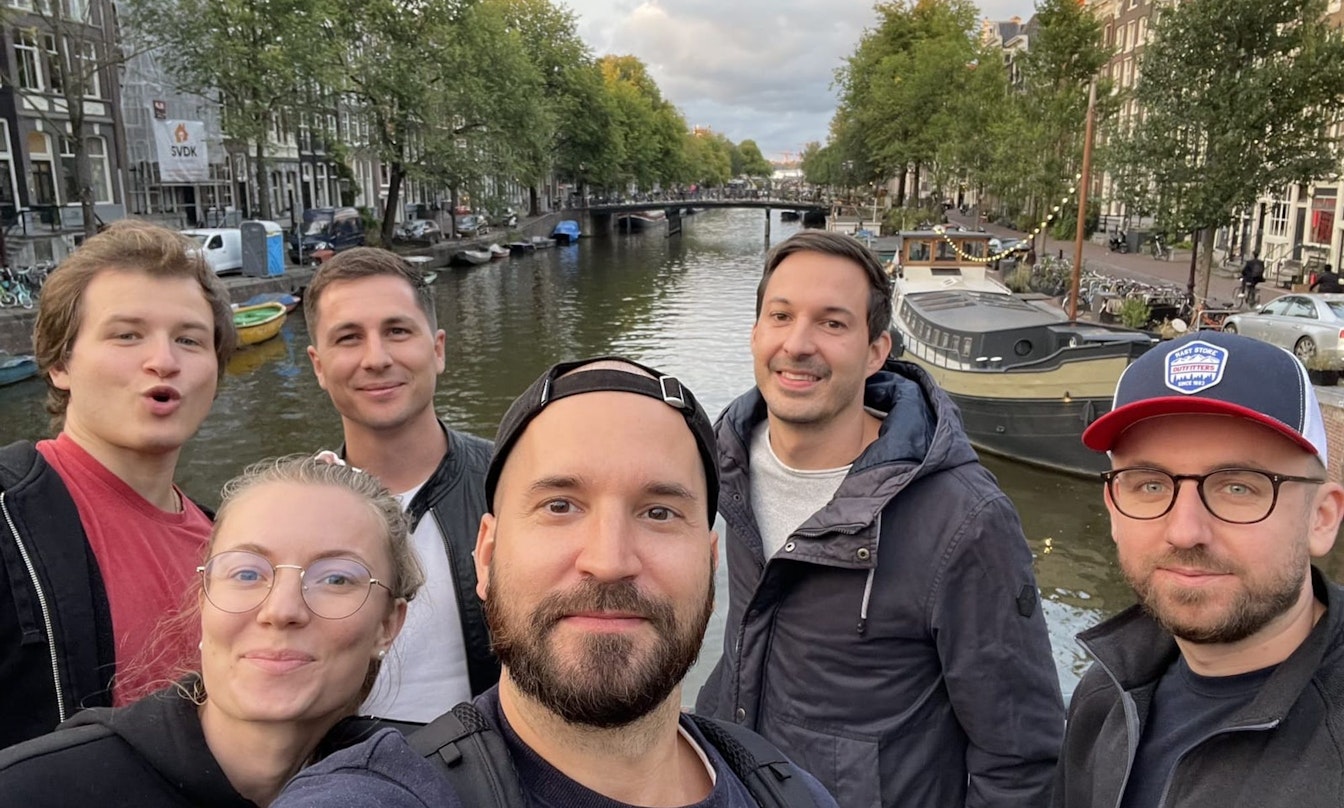 Smarties an der Awwwards Konferenz 2022 Eine Gruppe von sechs Personen macht ein Selfie auf einer Brücke mit einem Kanal und Gebäuden im Hintergrund.