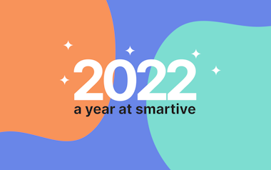 In der Mitte eines bunten Hintergrunds mit orangefarbenen und blaugrünen Klecksen und kleinen weißen Glitzersteinen steht ein fettgedruckter weißer Text: „2022, ein Jahr bei smartive“.