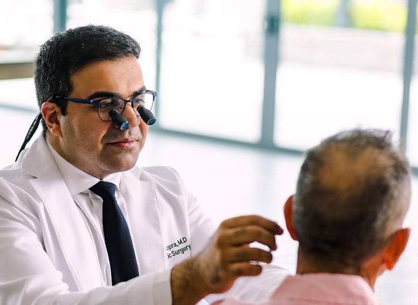 Dr. Chopra looking at male patient with special glasses on to see him