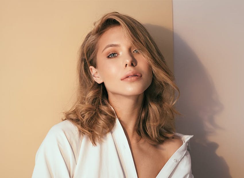 woman in white top leaning her head back on the wall