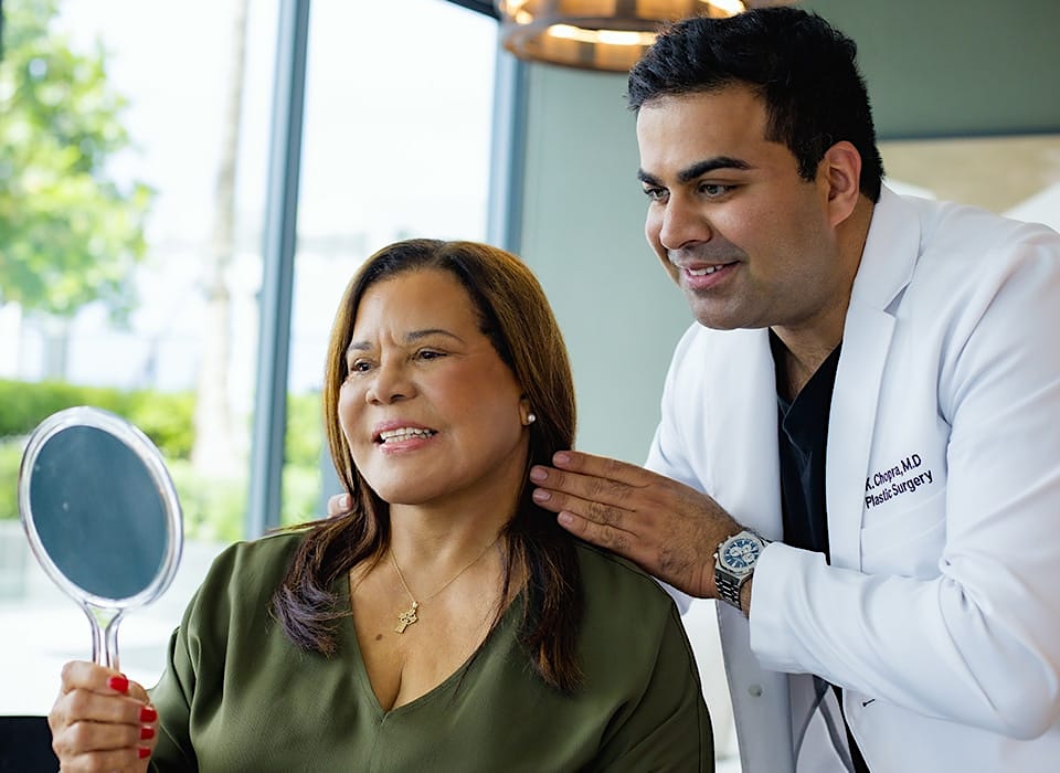 Dr. Chopra with patient both looking in handheld mirror