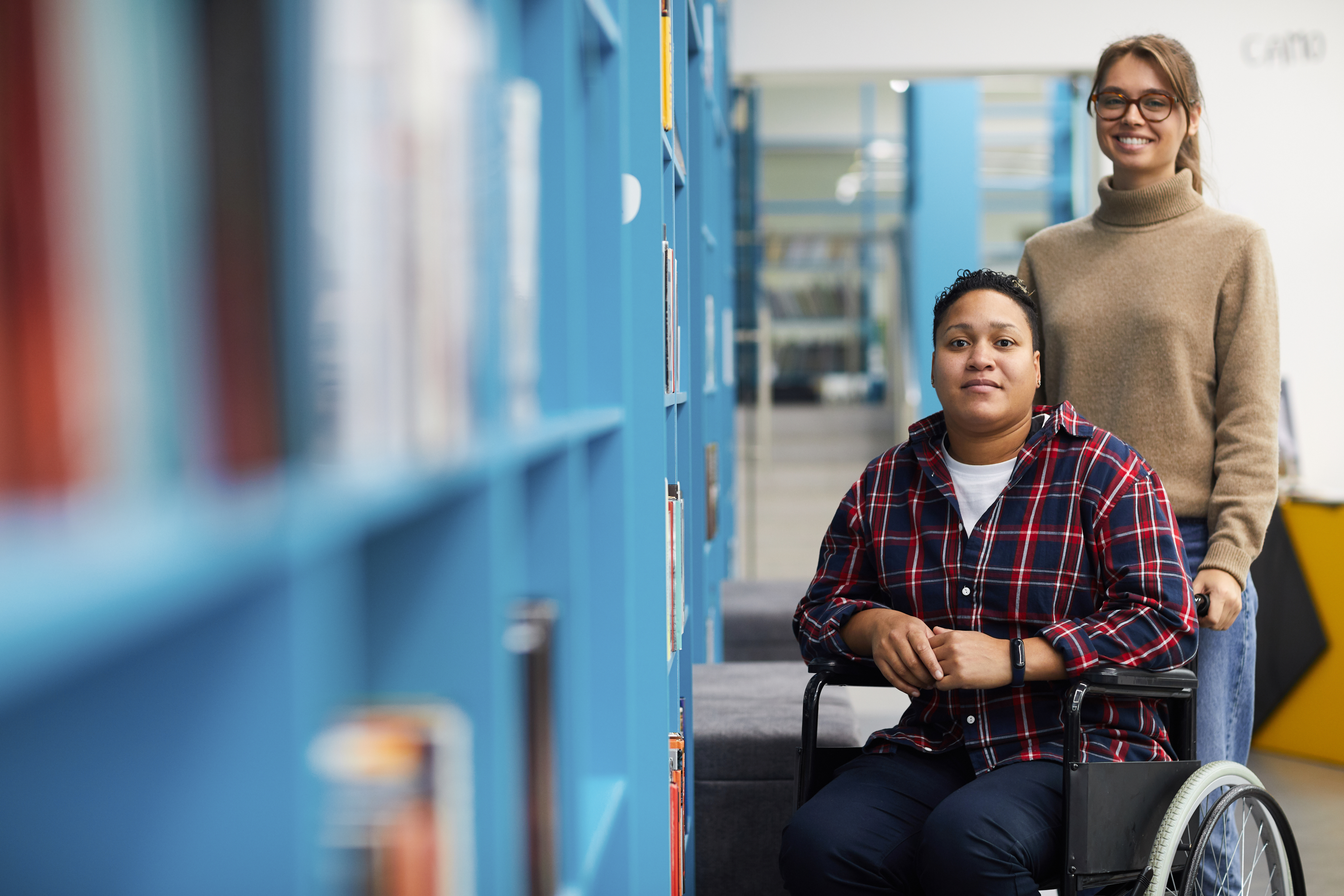 Mulher em pé segurando a cadeira de um cadeirante