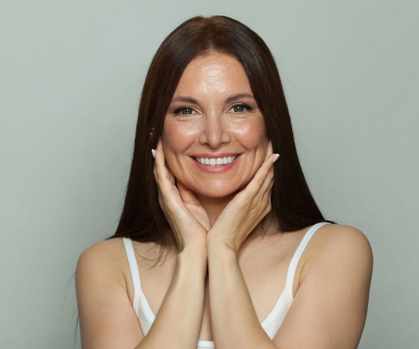 woman with her hands around her jaw smiling